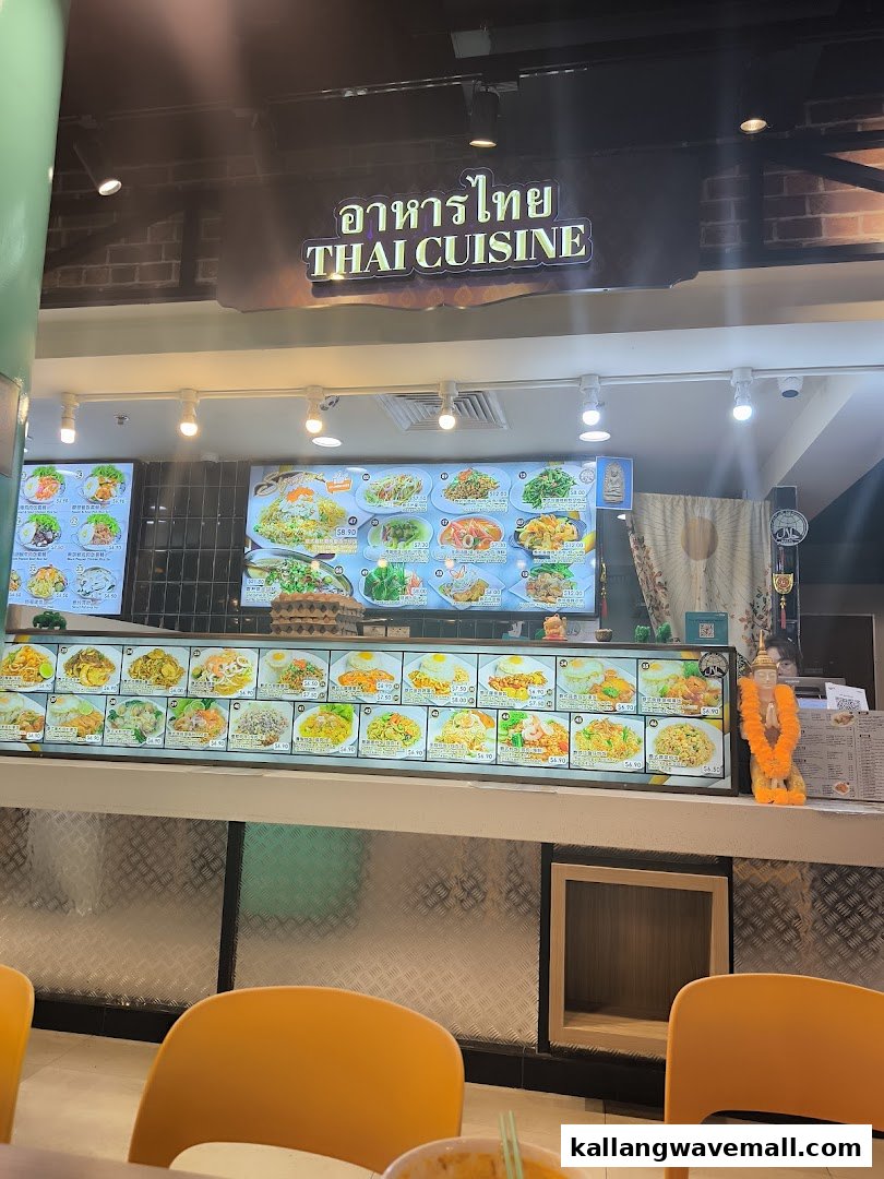 A vibrant Thai cuisine food stall with digital menu boards displaying various dishes and prices.