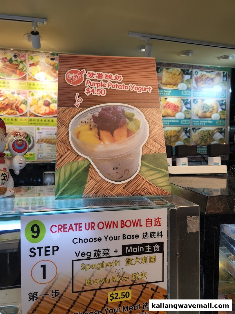 A close-up of a promotional sign for Purple Potato Yogurt and a 'Create Your Own Bowl' menu at My Kampung.