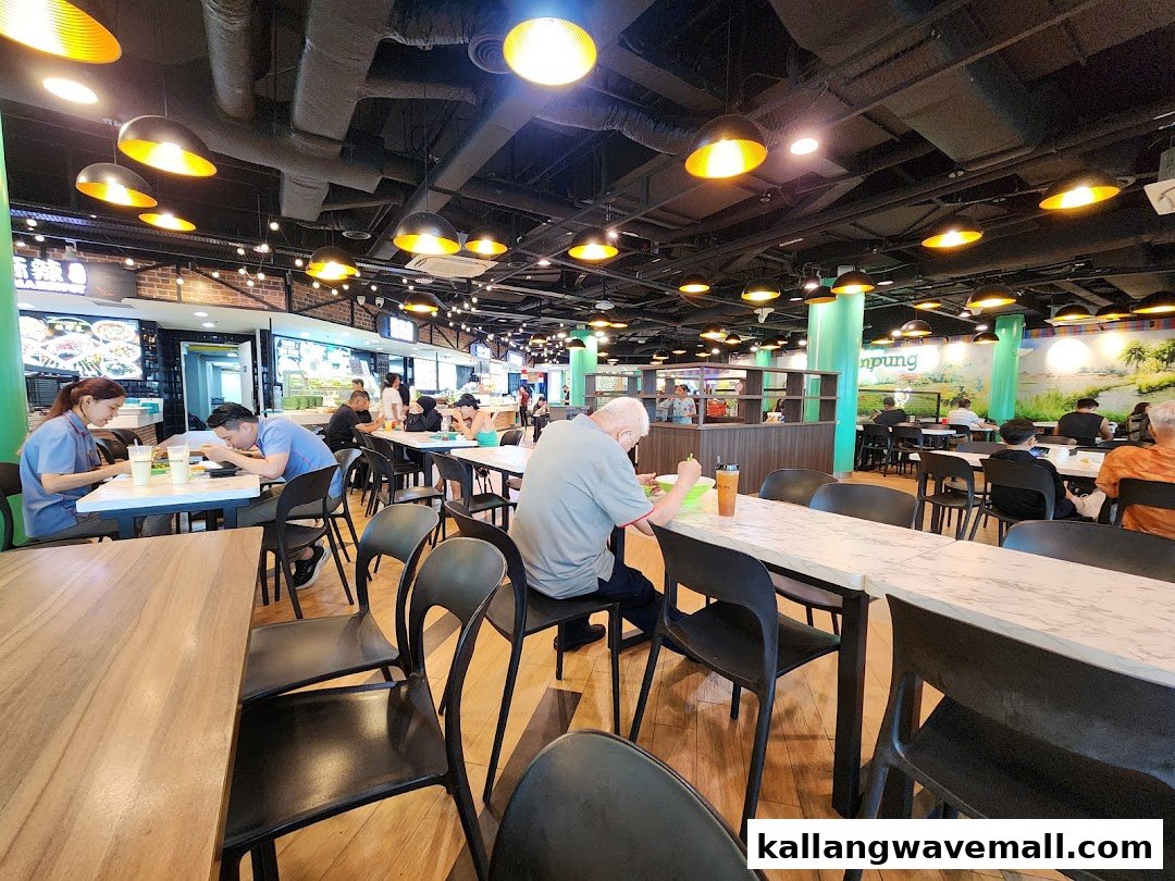 A bustling interior view of My Kampung food court with customers dining at various tables.