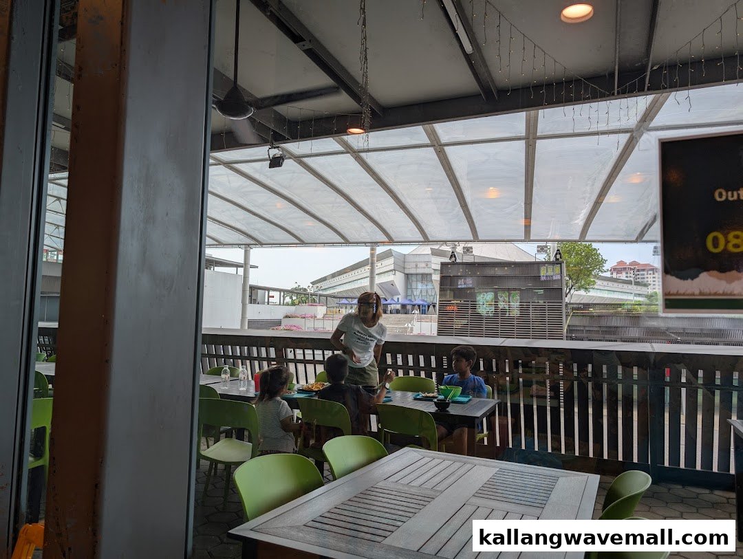 An interior view of My Kampung restaurant, showing diners in a spacious, open-air seating area with a view.