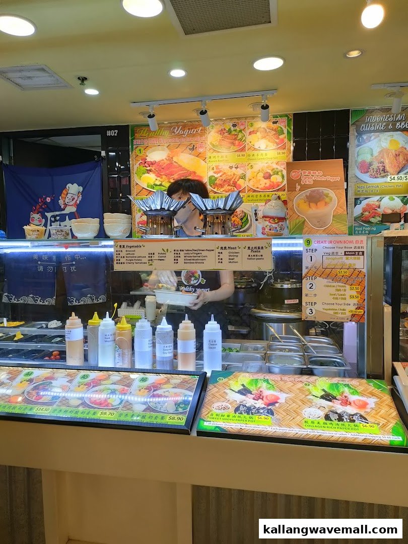A bustling food stall counter showcasing diverse dishes, fresh ingredients, and a staff member preparing food.