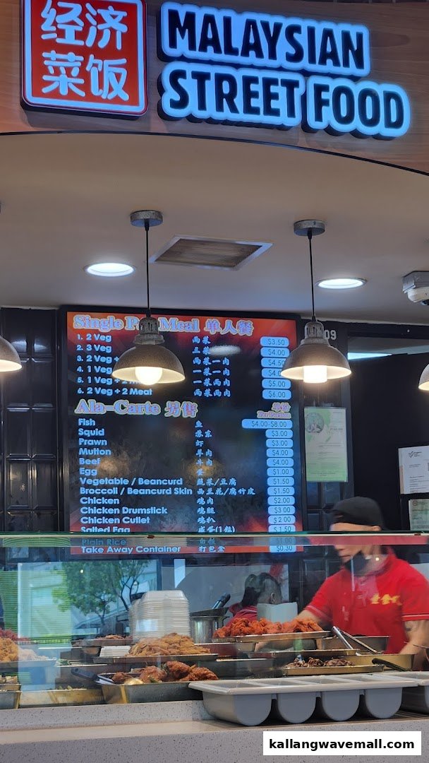 A vibrant Malaysian street food stall showcasing a variety of dishes and a clear menu board.