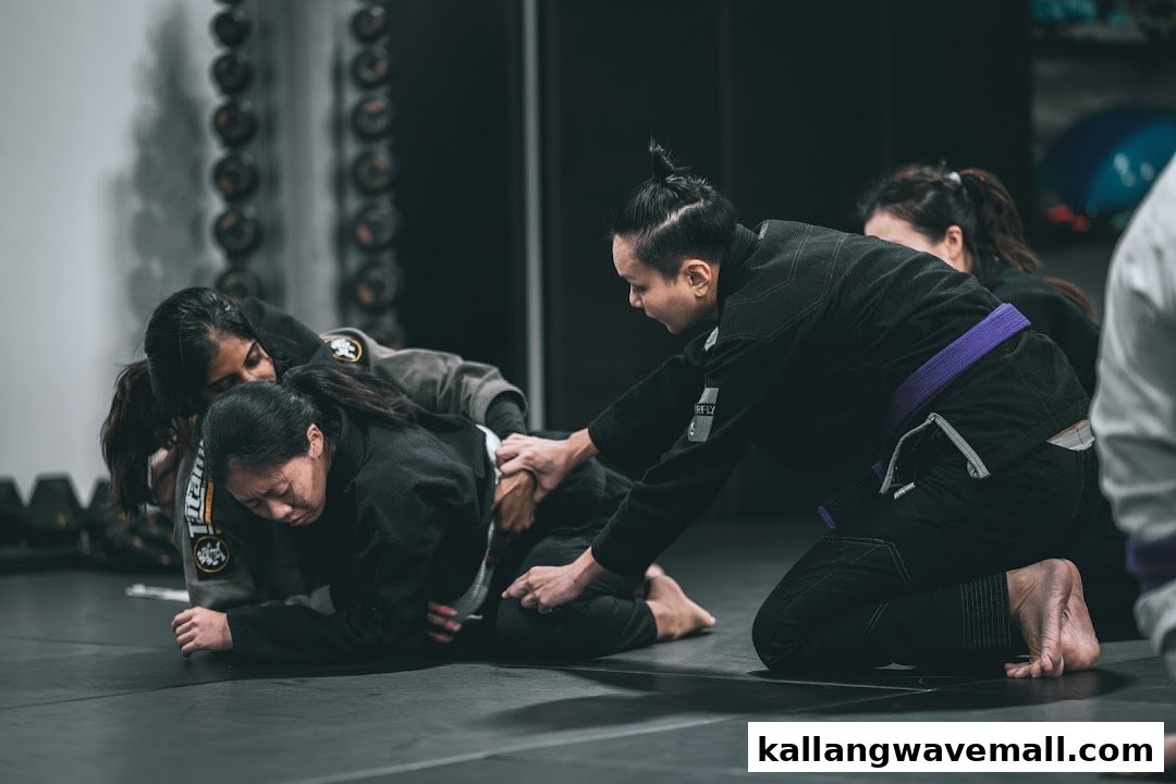 People in gis practicing martial arts techniques on a mat in a training facility.