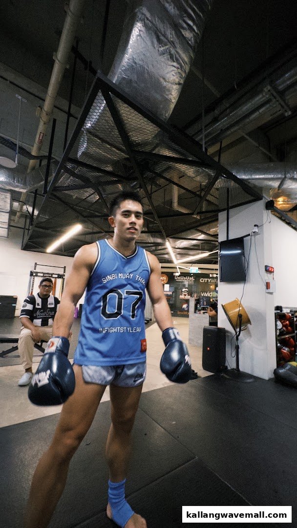 A person in boxing gear stands ready for training in a modern fitness gym.