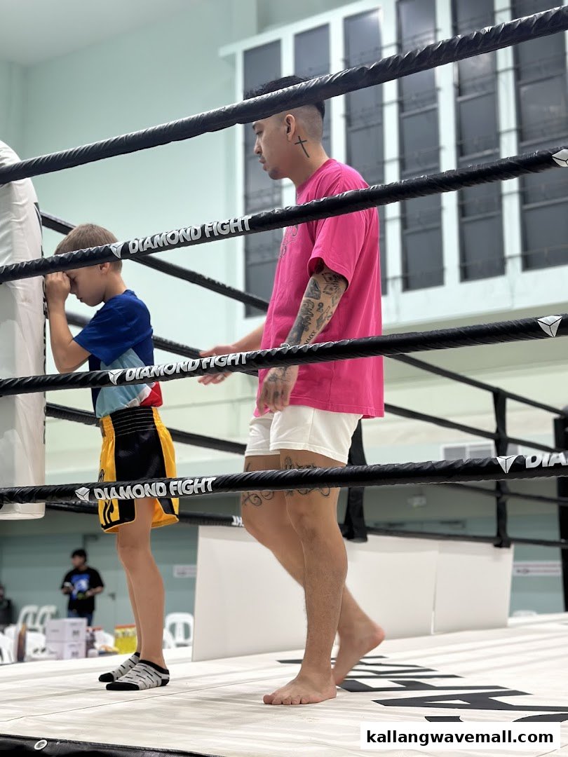 A trainer guides a young student in a boxing ring during a training session.