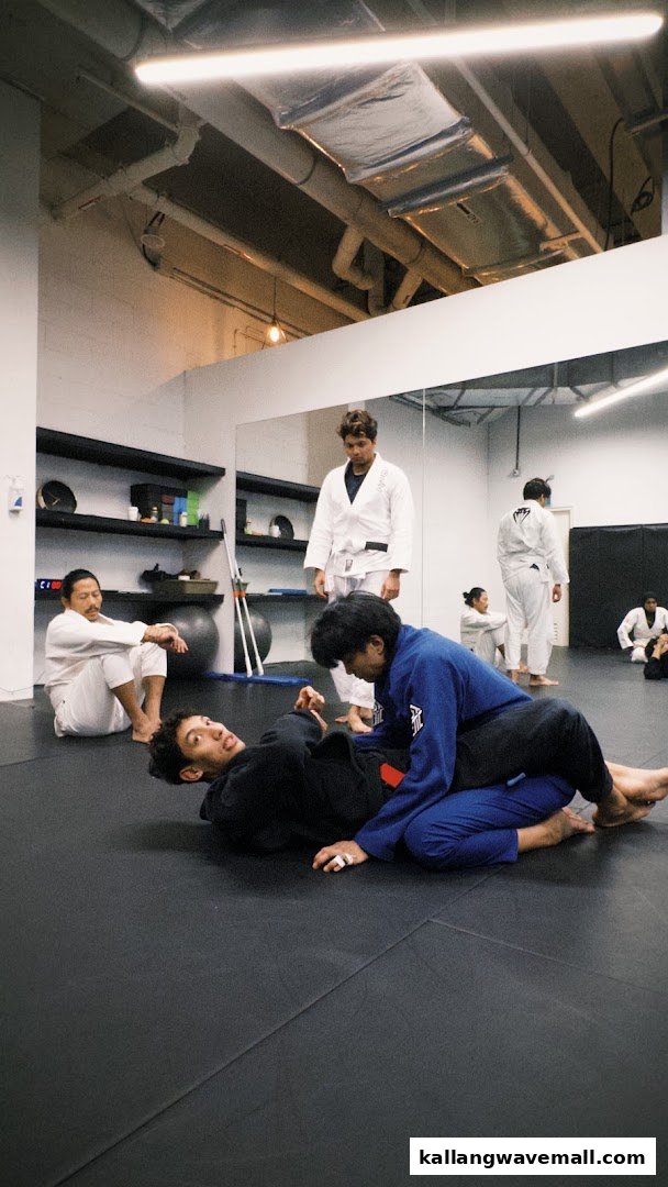 People in gis practicing martial arts on mats in a spacious training studio.