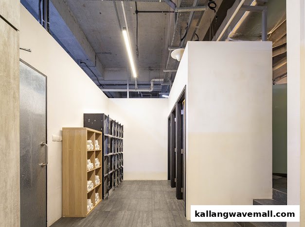 A clean, modern interior hallway with lockers, towel shelves, and changing room doors at Neue Fit.