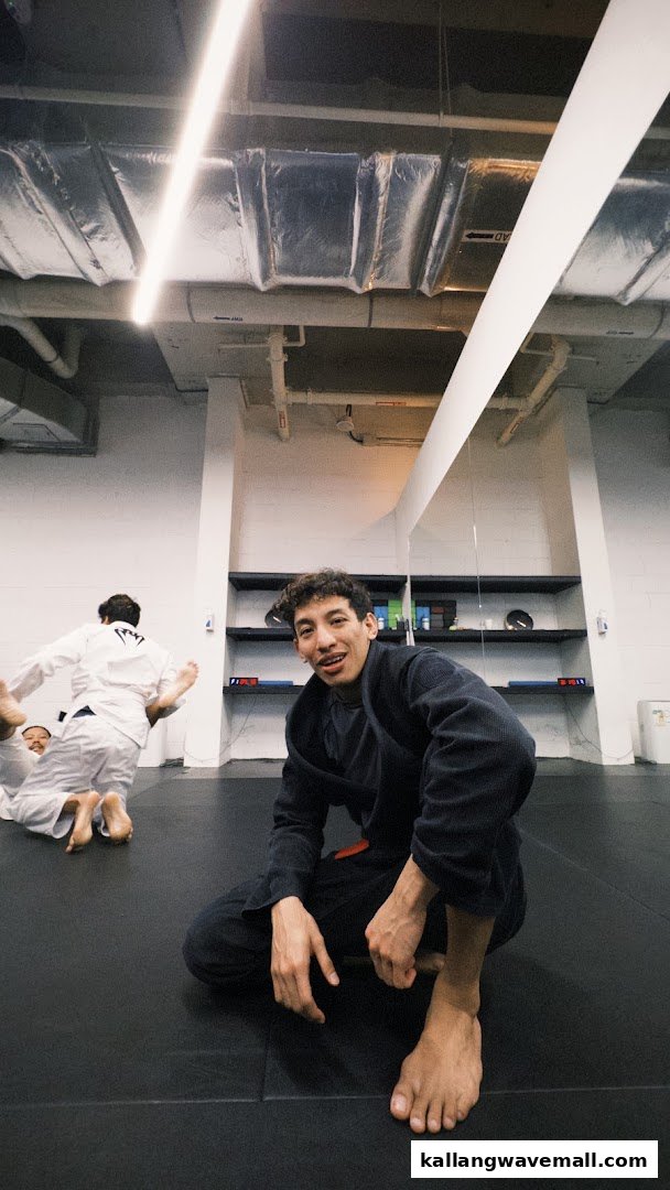 People training martial arts on mats inside a fitness studio, with one person looking at the camera.