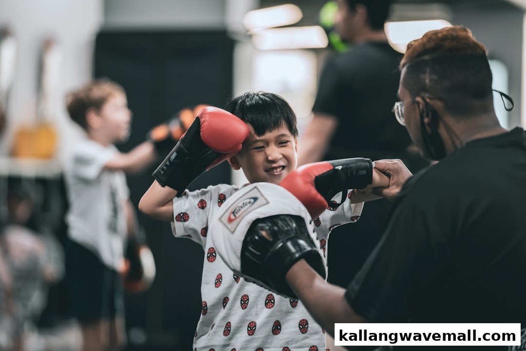 A child in boxing gloves smiles while training with an instructor at Neue Fit.
