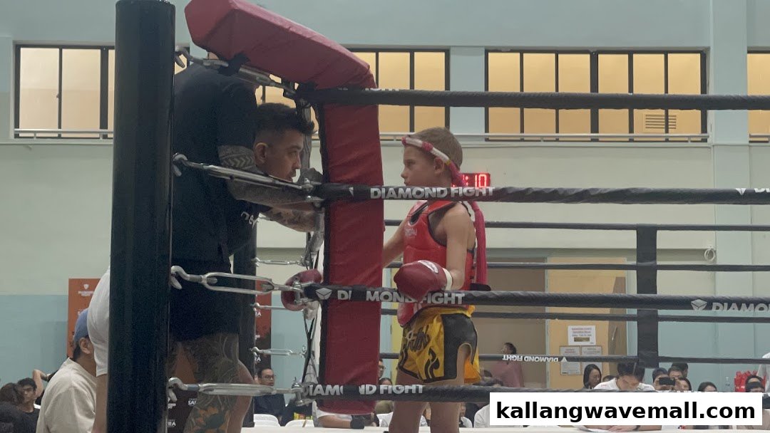An adult coach instructs a young fighter in a boxing ring during a Diamond Fight event.