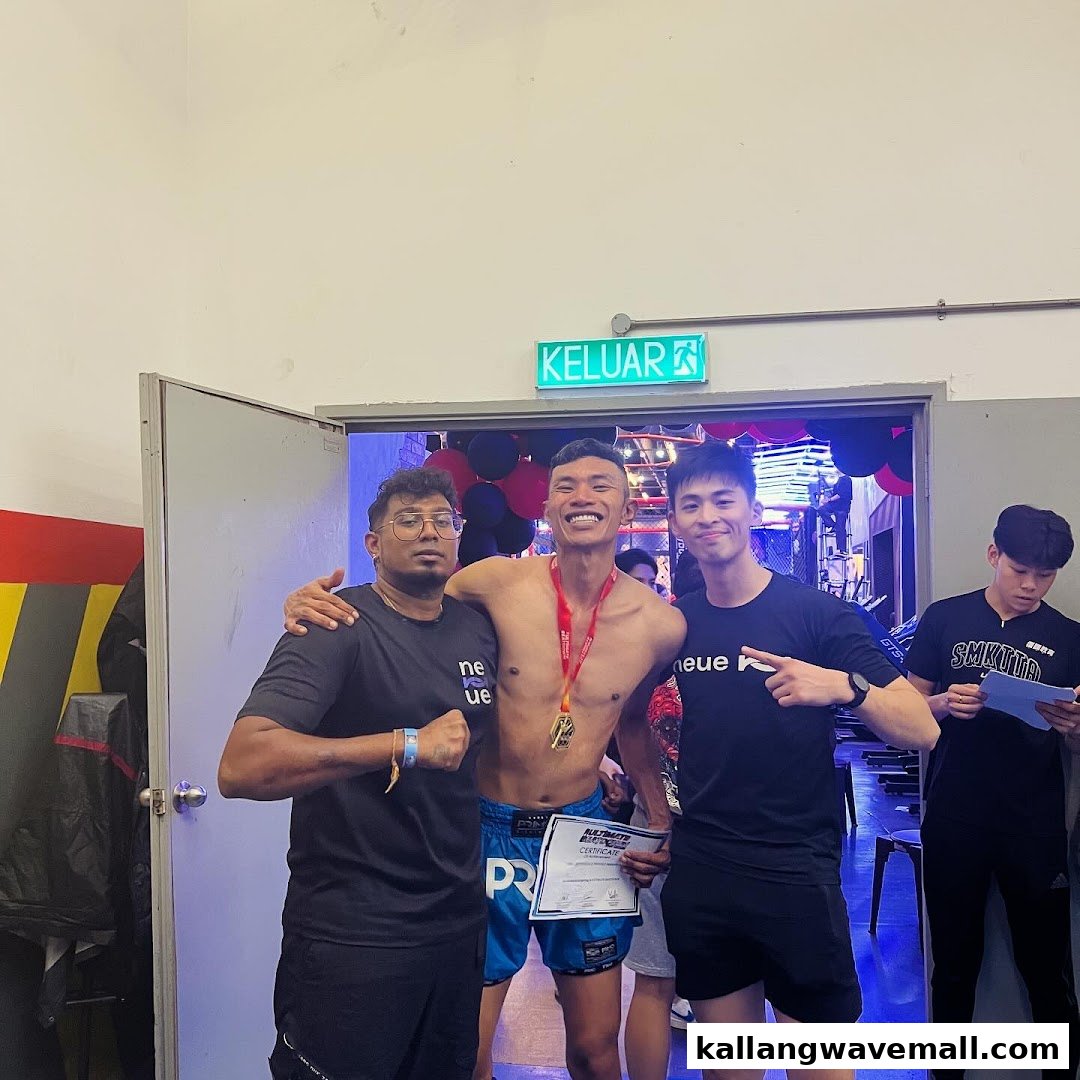 Three men, including a medalist, pose proudly inside Neue Fit's training facility after an event.