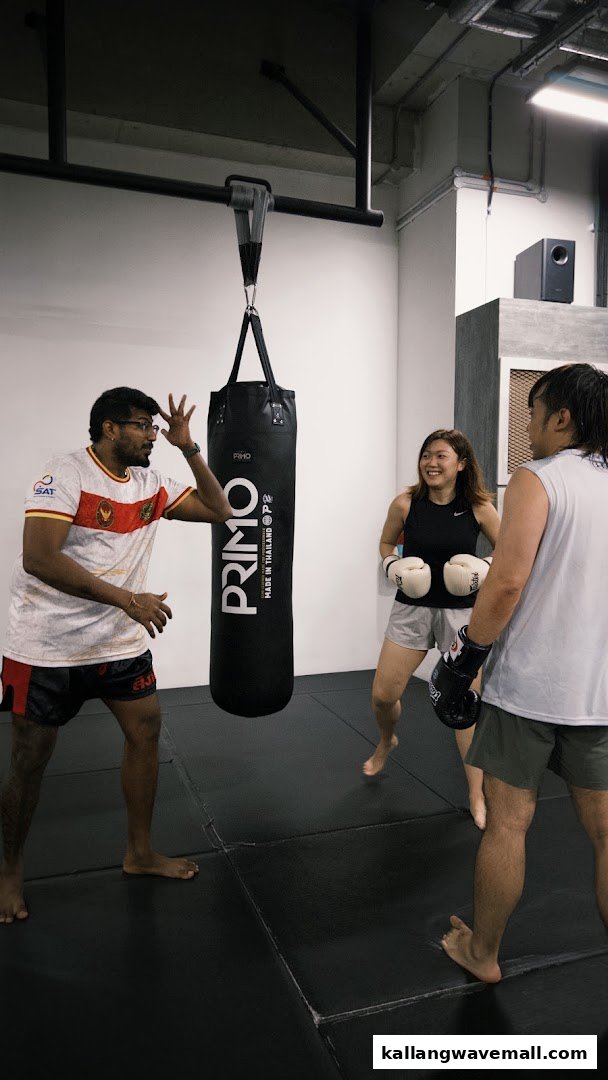 A trainer instructs two students during a dynamic boxing or Muay Thai session at Neue Fit.