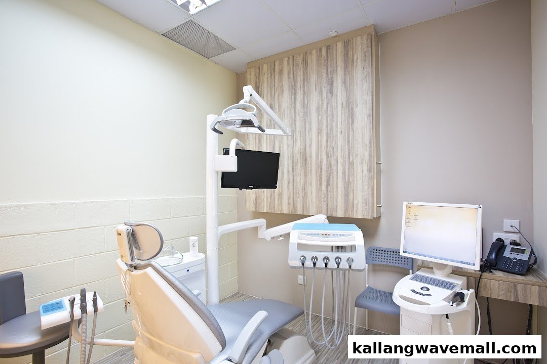 A modern dental treatment room with a patient chair, dental equipment, and computer setup.