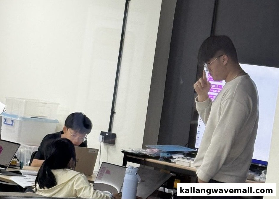 An instructor guides students learning robotics and coding with laptops in a bright classroom setting.