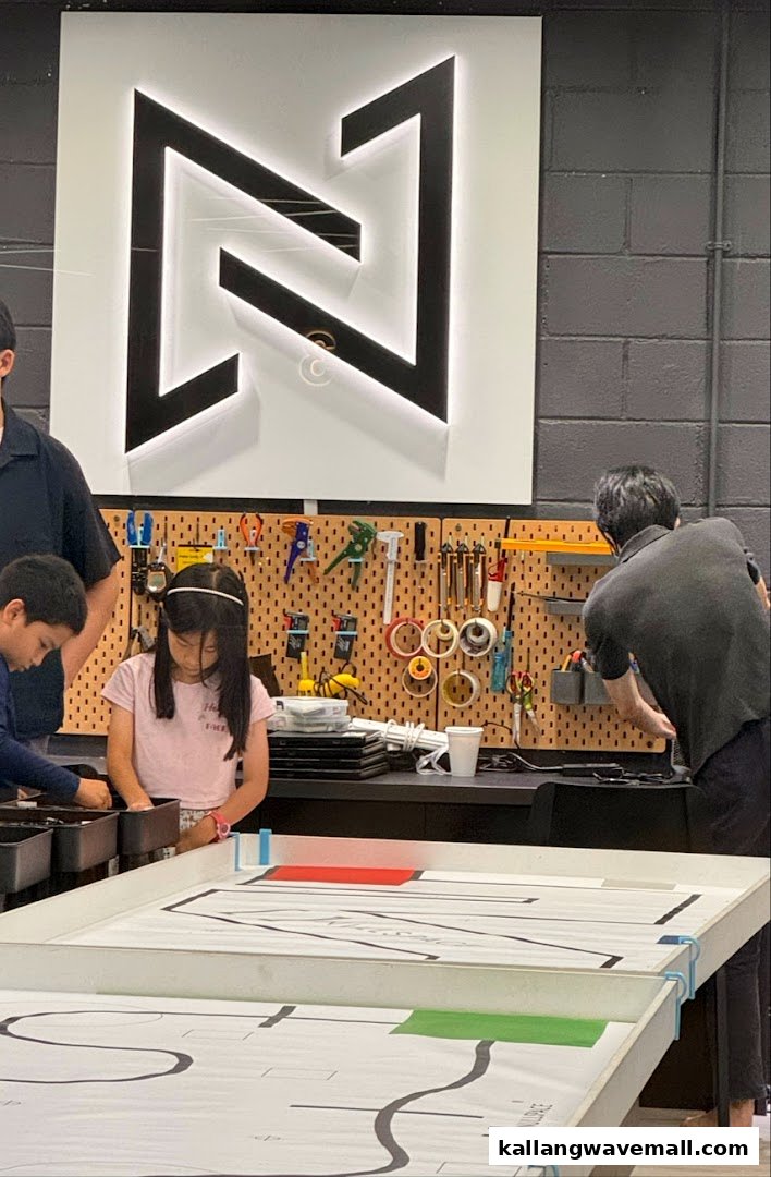Children and adults engaged in robotics activities at Nullspace Robotics, with the shop's logo prominently displayed.