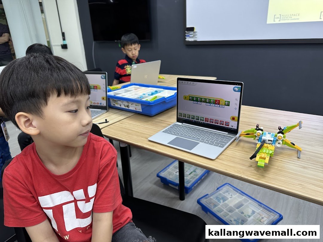 Children engaged in a robotics class, coding on laptops with Lego models and building kits.