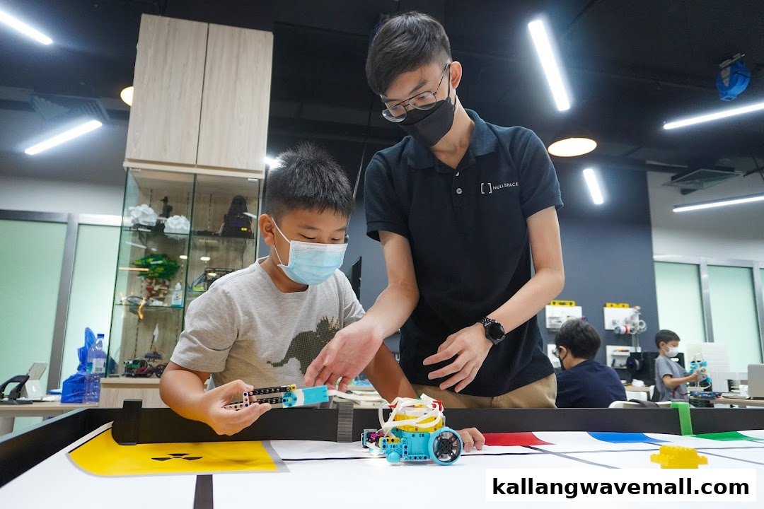 An instructor guides a child building a robot on a competition mat at Nullspace Robotics.