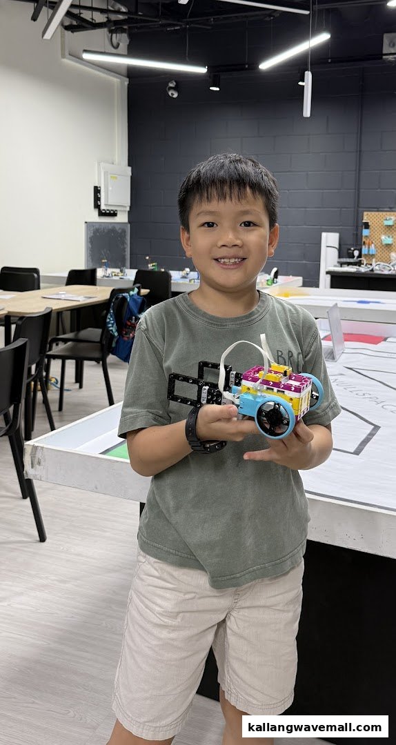 A young boy proudly holds a colorful robot he built at Nullspace Robotics.