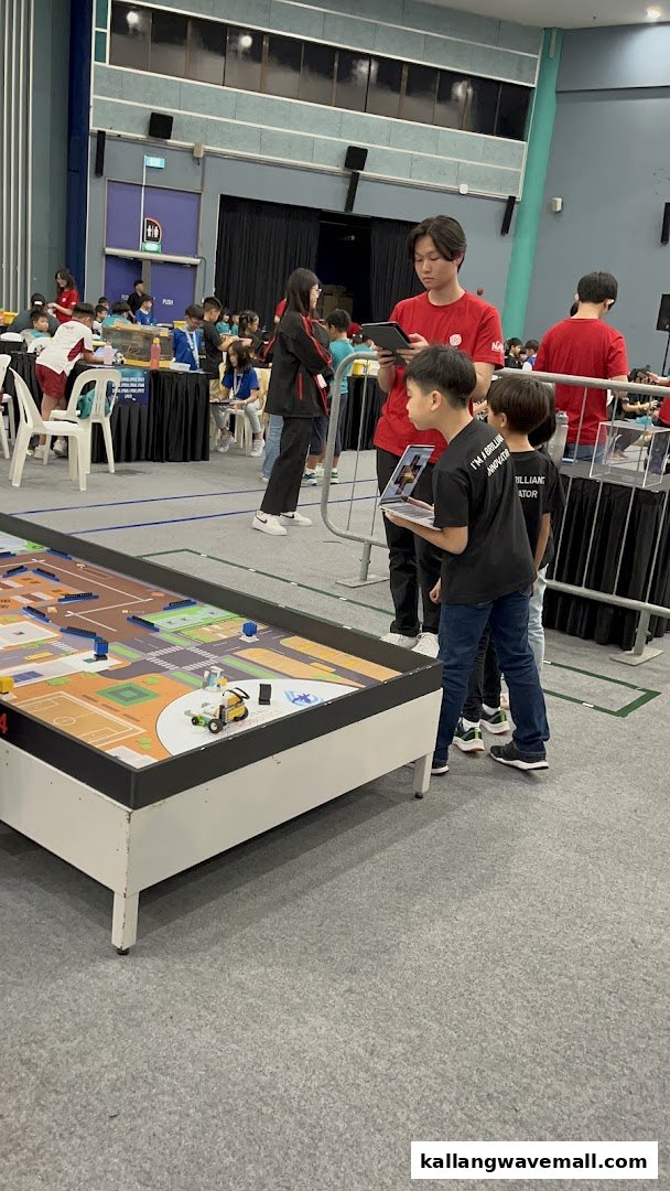 Kids and adults engaged in a robotics competition or workshop, featuring a robot on a patterned table.