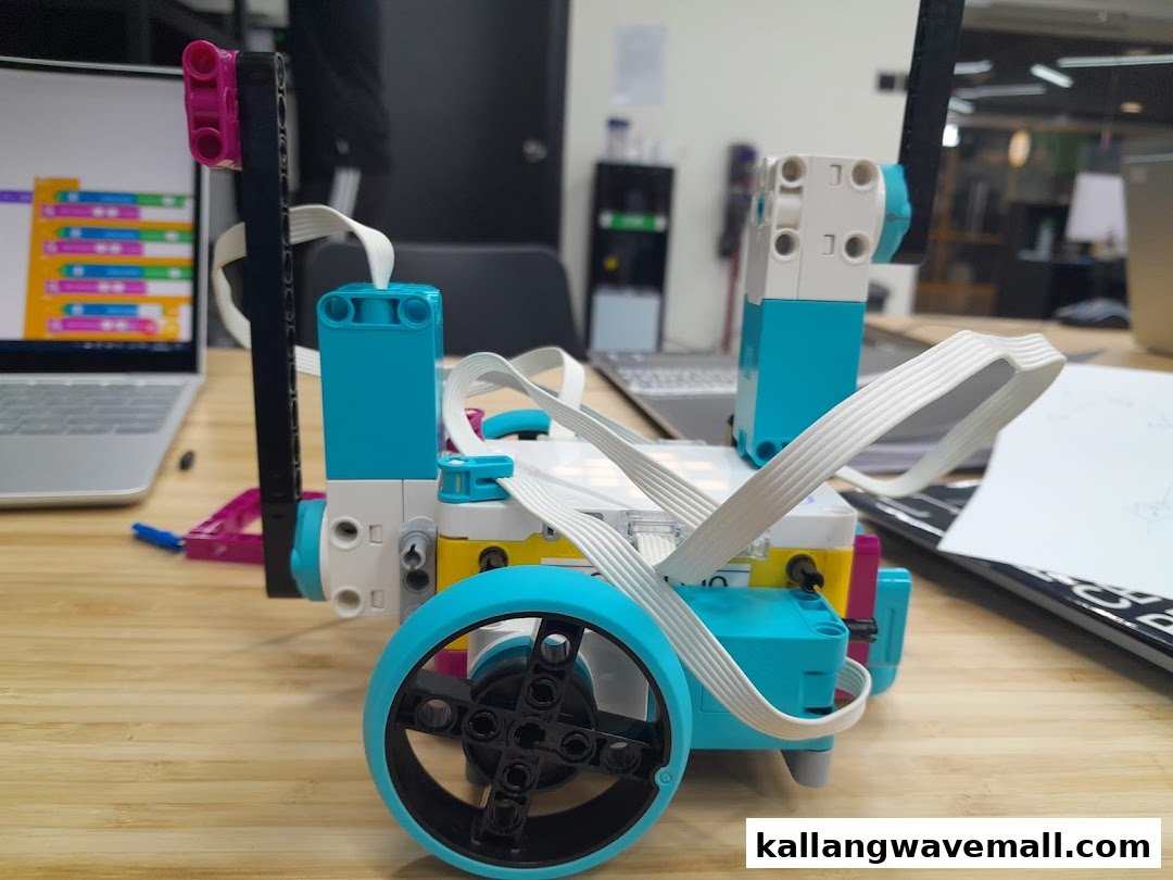 A colorful robot built with Lego-like bricks on a wooden table, with a laptop displaying code.