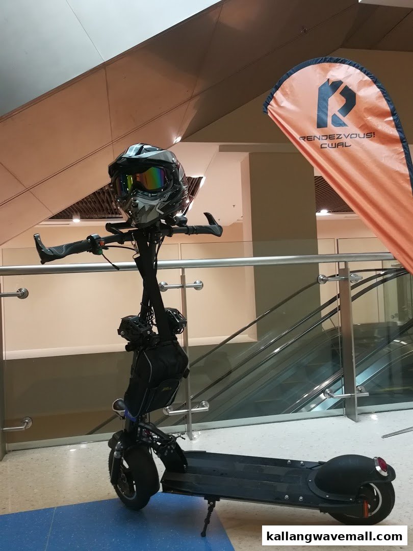An electric scooter with a helmet displayed in a mall, showcasing O-Ride's adventure offerings.