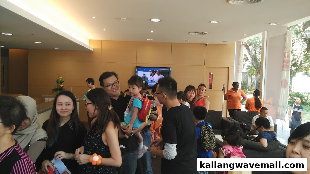A lively indoor scene showing a diverse group of people, including families, in a waiting area.