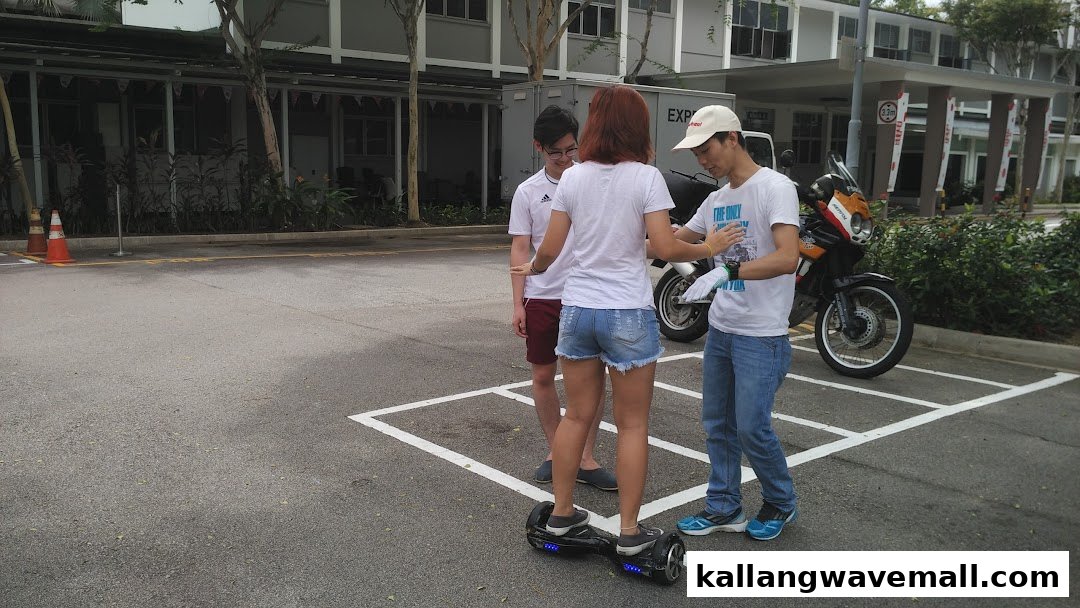 An instructor guides a customer learning to ride a mini segway outdoors.