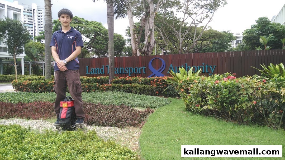 A young man stands on a mini segway-like device outdoors, ready for adventure.
