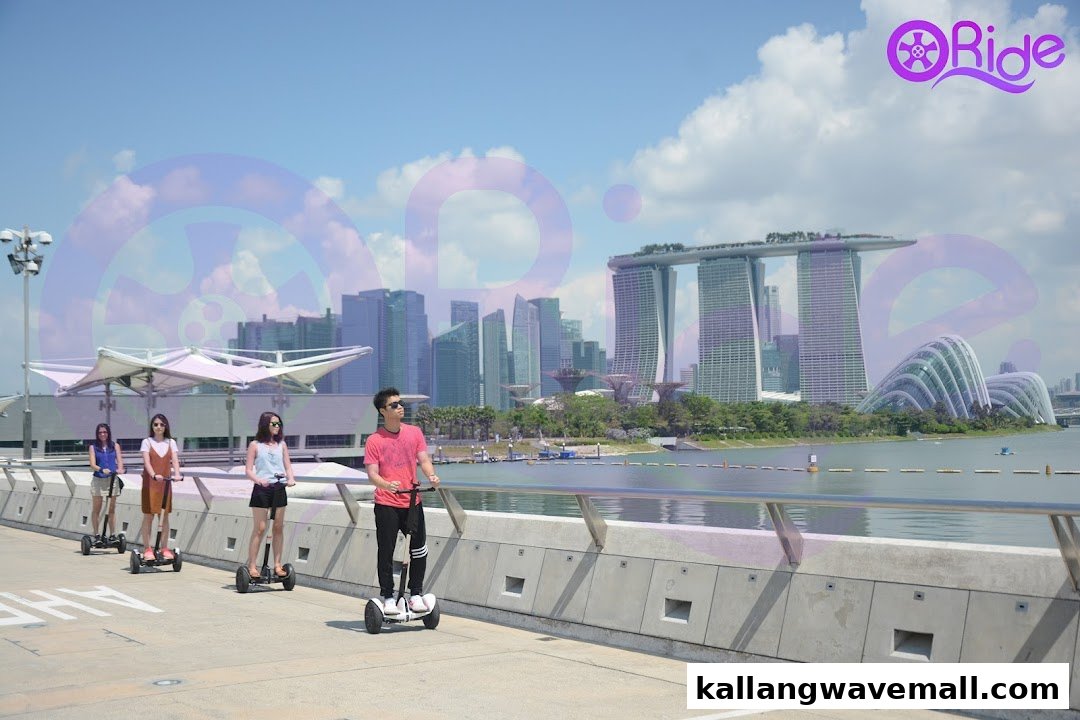 People riding mini segways along a waterfront promenade with the Singapore skyline in the background.