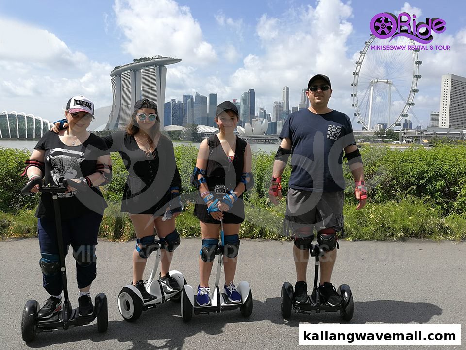 Four people on mini segways with Singapore's iconic skyline, including Marina Bay Sands, in the background.