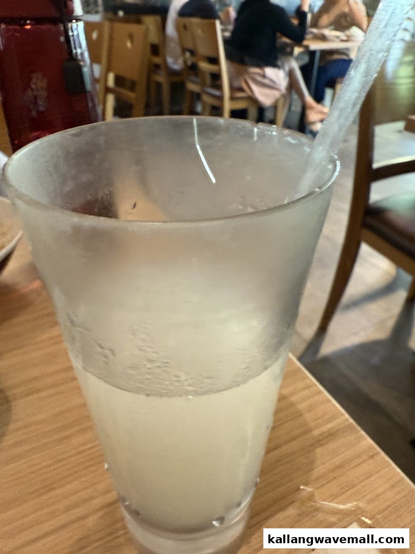 A refreshing cold drink in a frosted glass on a wooden table inside the restaurant.