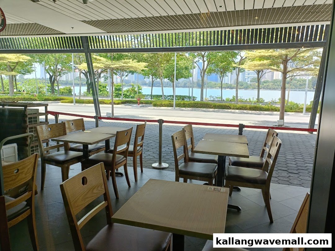 Spacious restaurant interior featuring wooden tables and chairs, offering a scenic waterfront view.