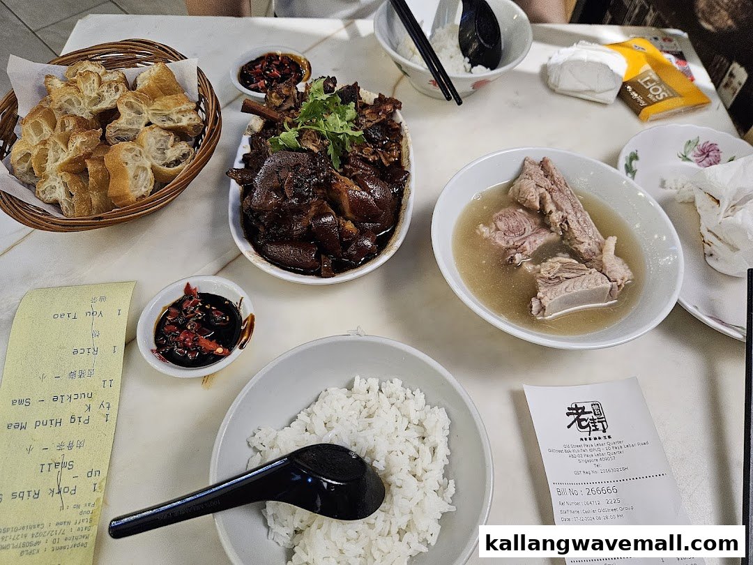 A table laden with traditional Bak Kut Teh, braised pig trotters, rice, and fried dough sticks.