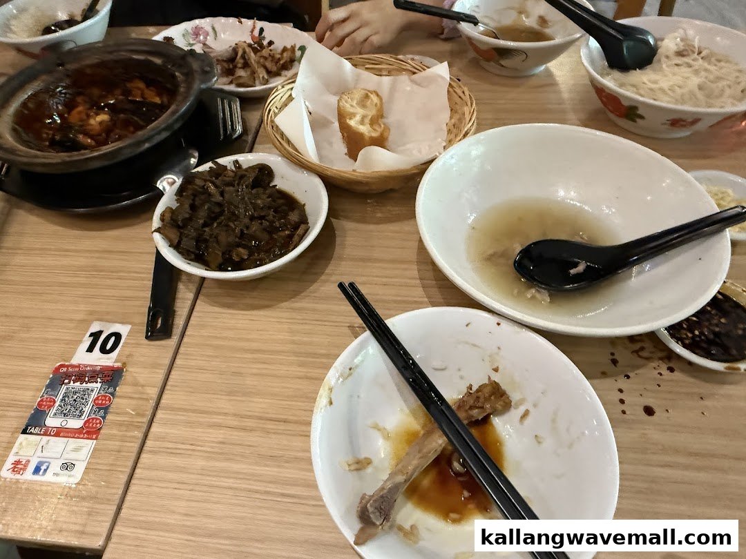 A table laden with various dishes, including a claypot of Bak Kut Teh, and used bowls.
