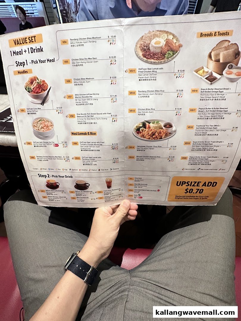 A person holds an Oldtown White Coffee menu displaying various Malaysian dishes and drinks.