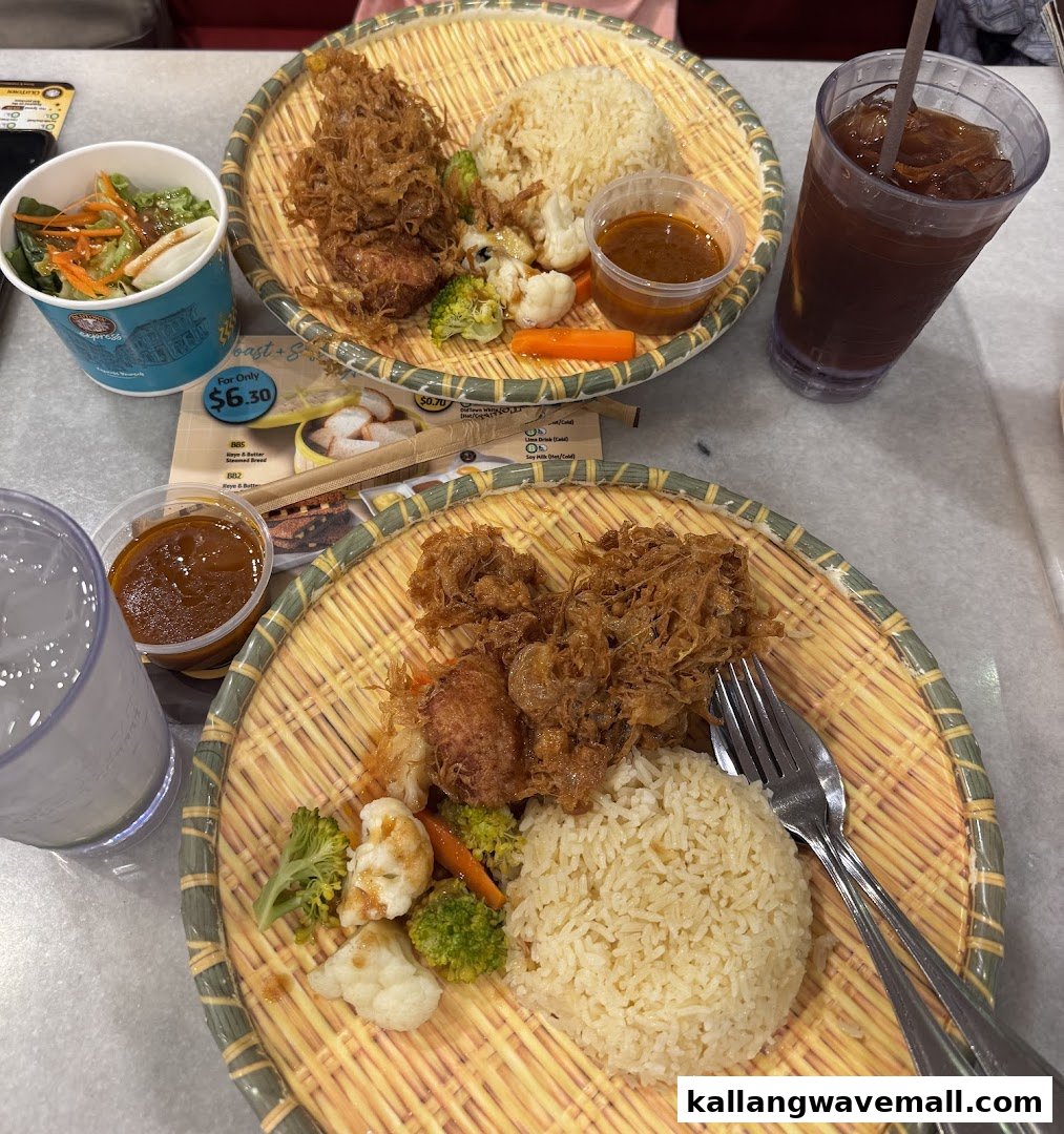 Two traditional Asian rice sets with fried chicken, vegetables, sauces, and drinks on a table.