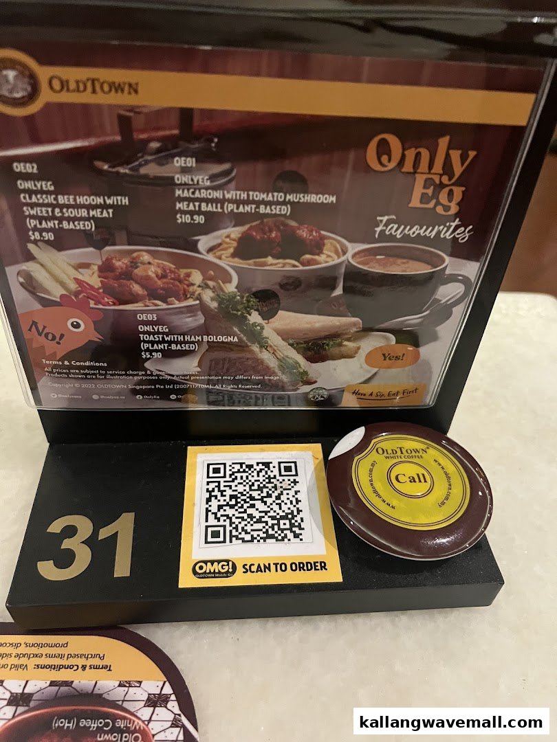 A table-top menu display at Oldtown White Coffee featuring plant-based 'Only Eg Favourites' and a 'Scan to Order' QR code.