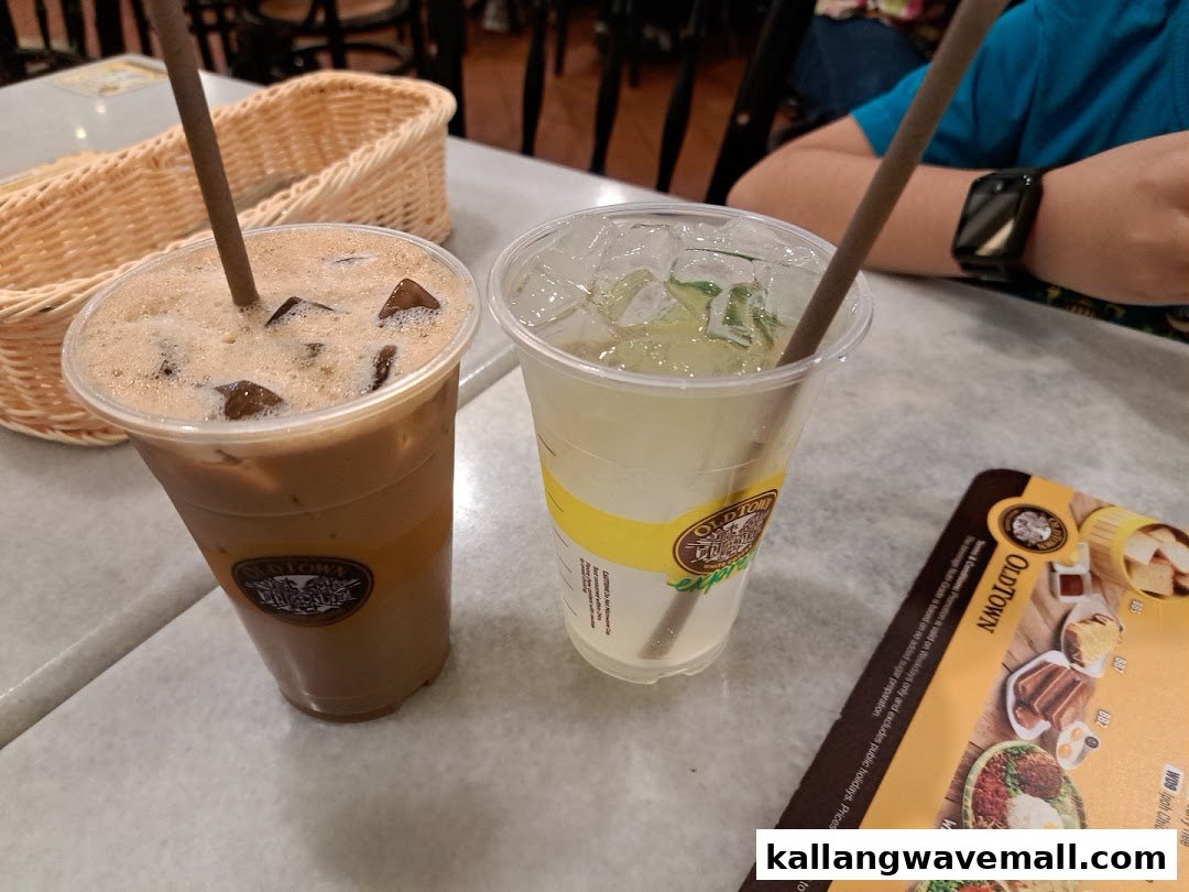 Two refreshing iced beverages from Oldtown White Coffee on a table, with a partial menu visible.
