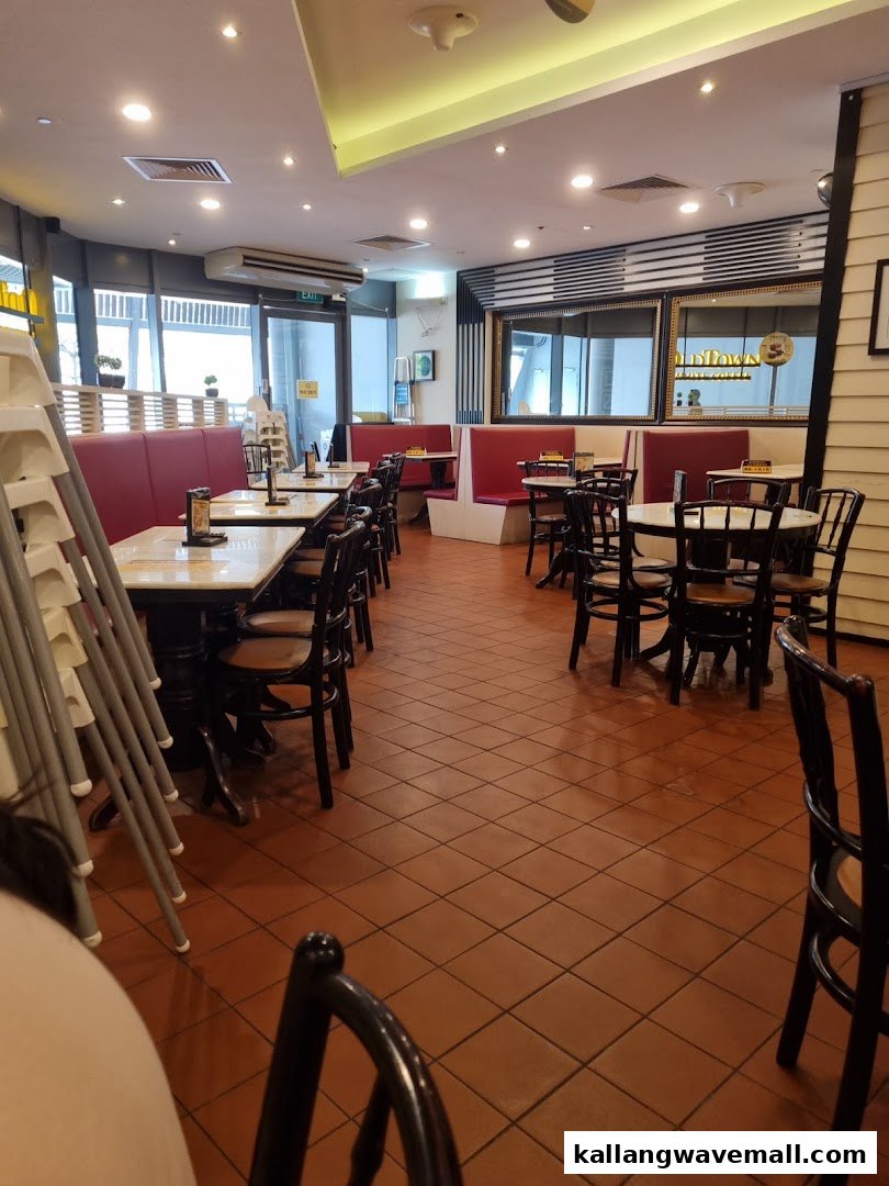Interior view of Oldtown White Coffee with tables, chairs, and red booth seating.