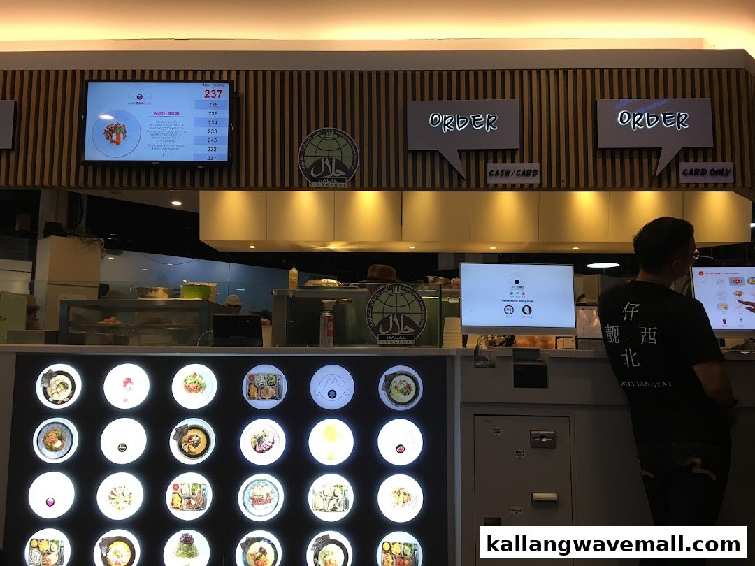 A bustling OMOOMO counter with digital screens, a vibrant food display, and a customer.