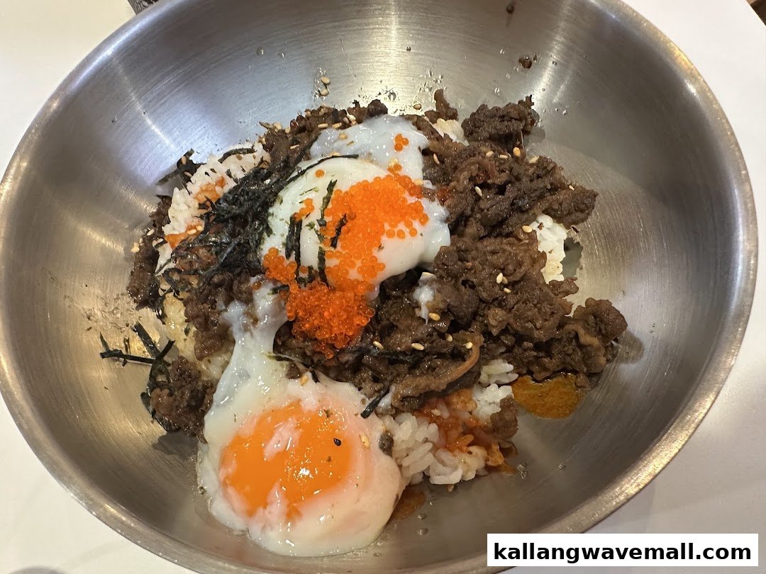 A close-up of a delicious Korean-style rice bowl with beef, poached eggs, and fish roe.