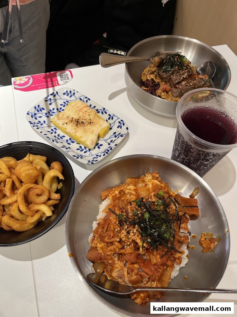 A table laden with delicious Korean-inspired rice bowls, curly fries, tamagoyaki, and a drink.