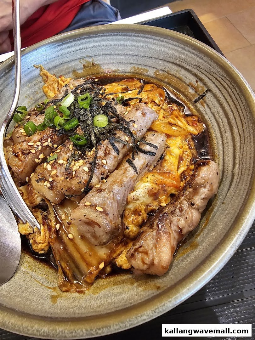 A close-up of a delicious bowl featuring grilled beef slices, kimchi, and rice, garnished with spring onions and seaweed.