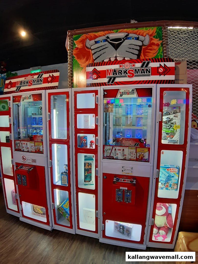 A row of red and white arcade prize machines filled with various toys and electronics.
