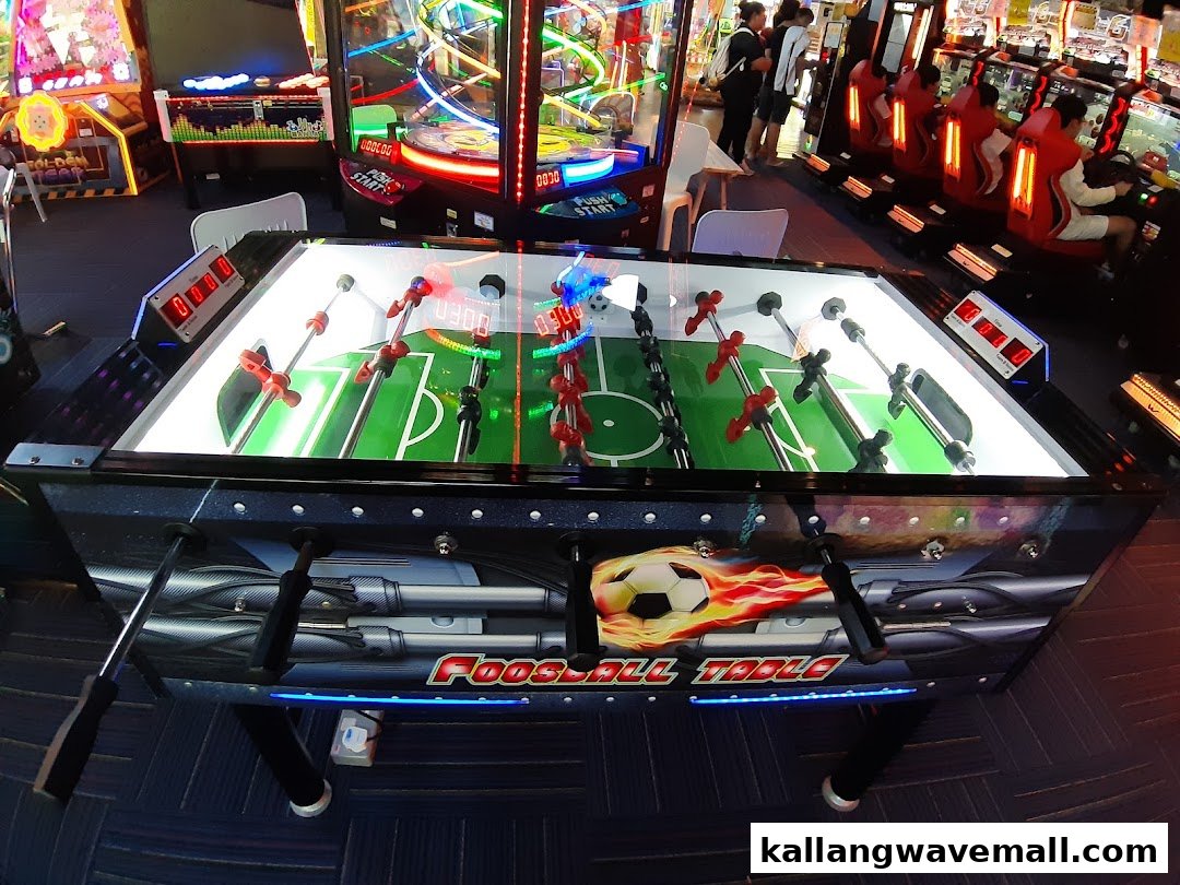 A vibrant arcade interior featuring a foosball table and various other brightly lit game machines.