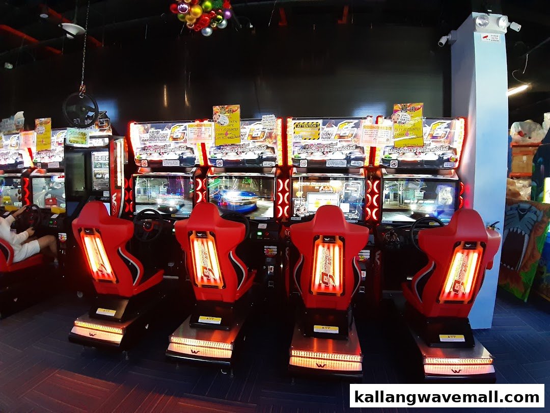 An arcade features multiple racing game machines with red seats, inviting players to compete.
