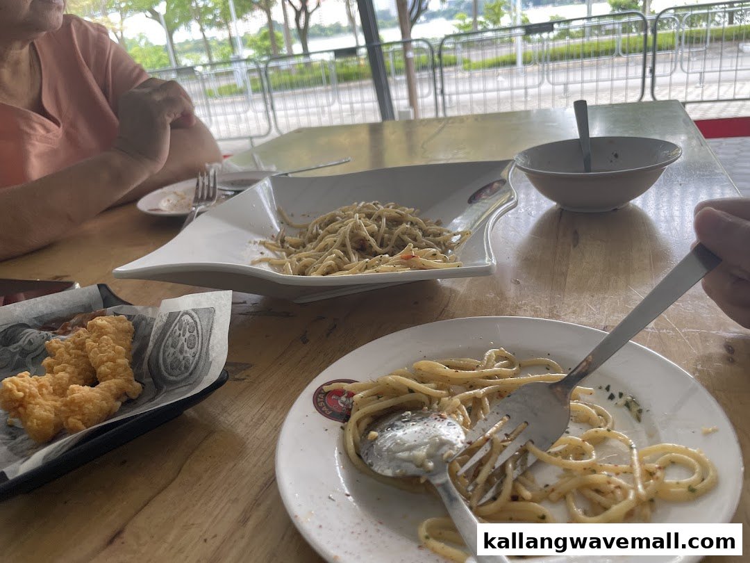 Diners enjoying pasta and fried chicken at a table with a view of the outdoors.