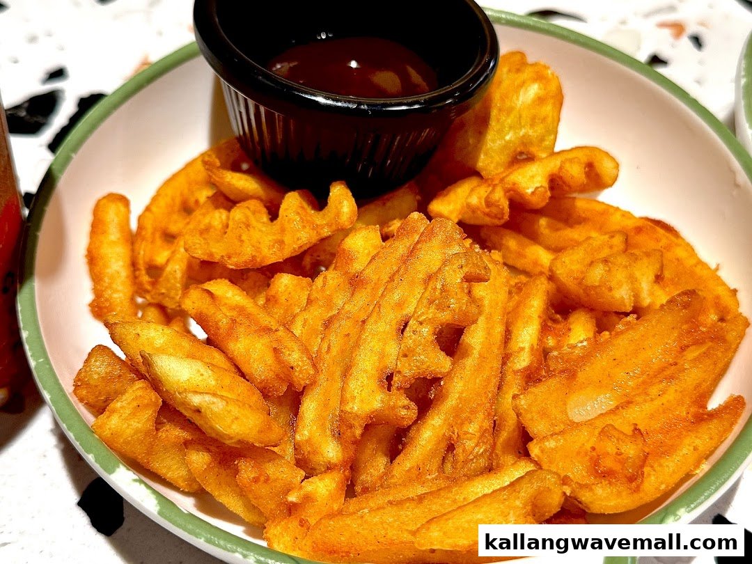 A close-up of golden-brown waffle fries served in a bowl with a side of dipping sauce.
