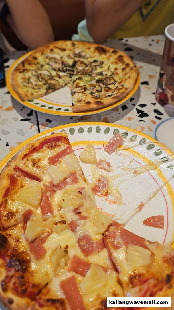 Two delicious pizzas, one with pineapple and ham, the other with mushrooms, on a table.