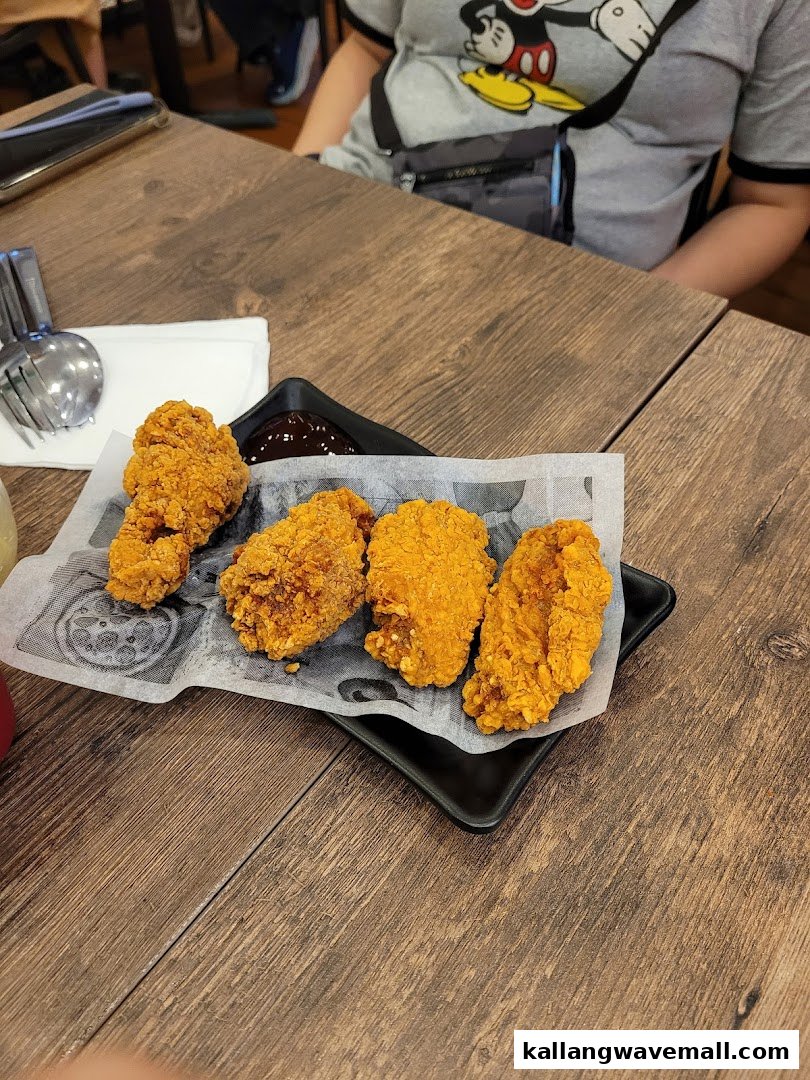 A plate of crispy fried chicken pieces with dipping sauce on a wooden table.